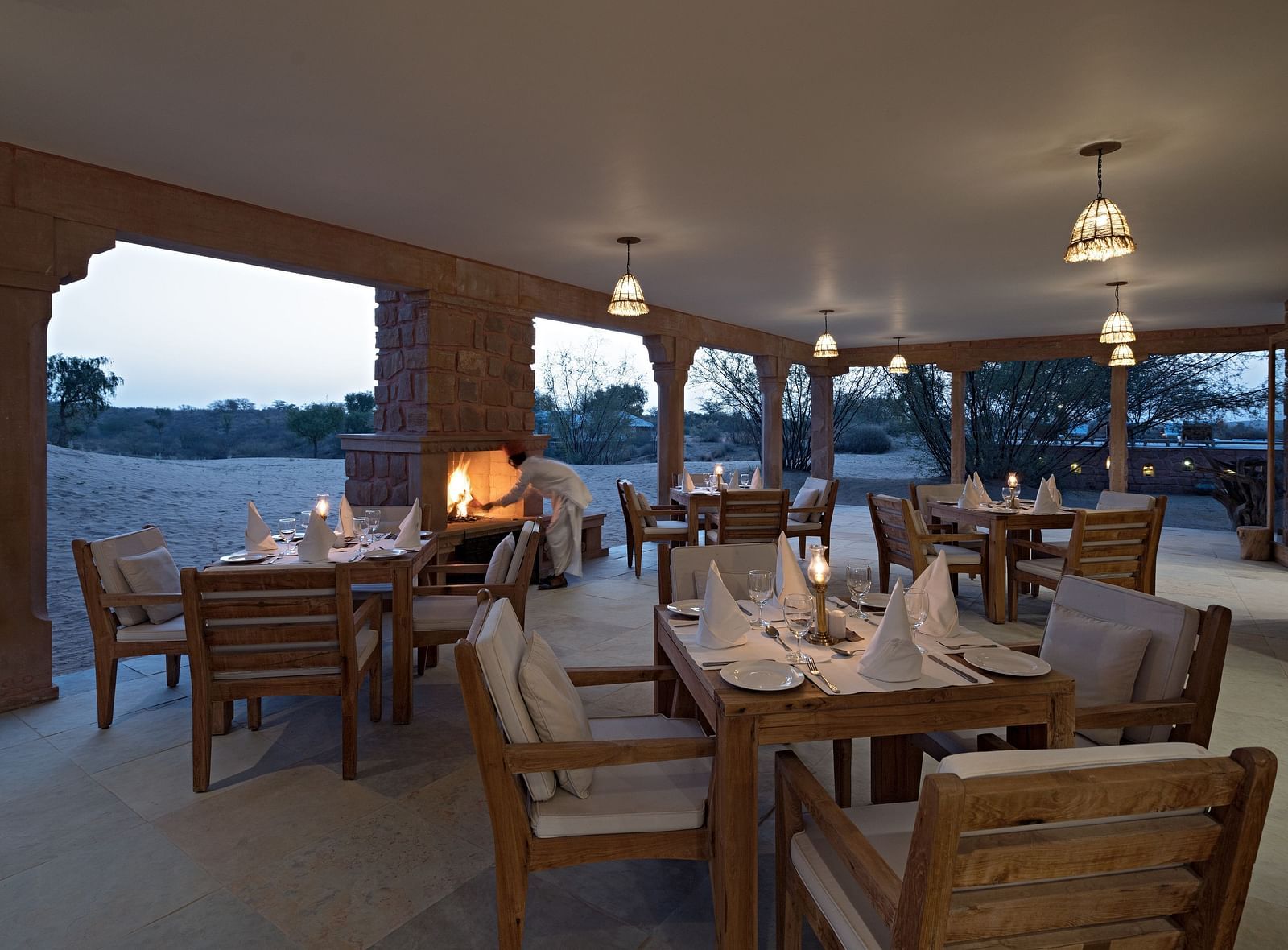 An image of a restaurant with its seating arrangement which is brightly lit with decorative lighting over looking the desert - MANVAR Resort & Desert Camp