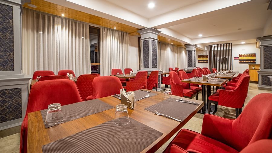 Dining area in Sumitel Hotel with red cushioned chairs and set tables, modern and cosy ambience. 