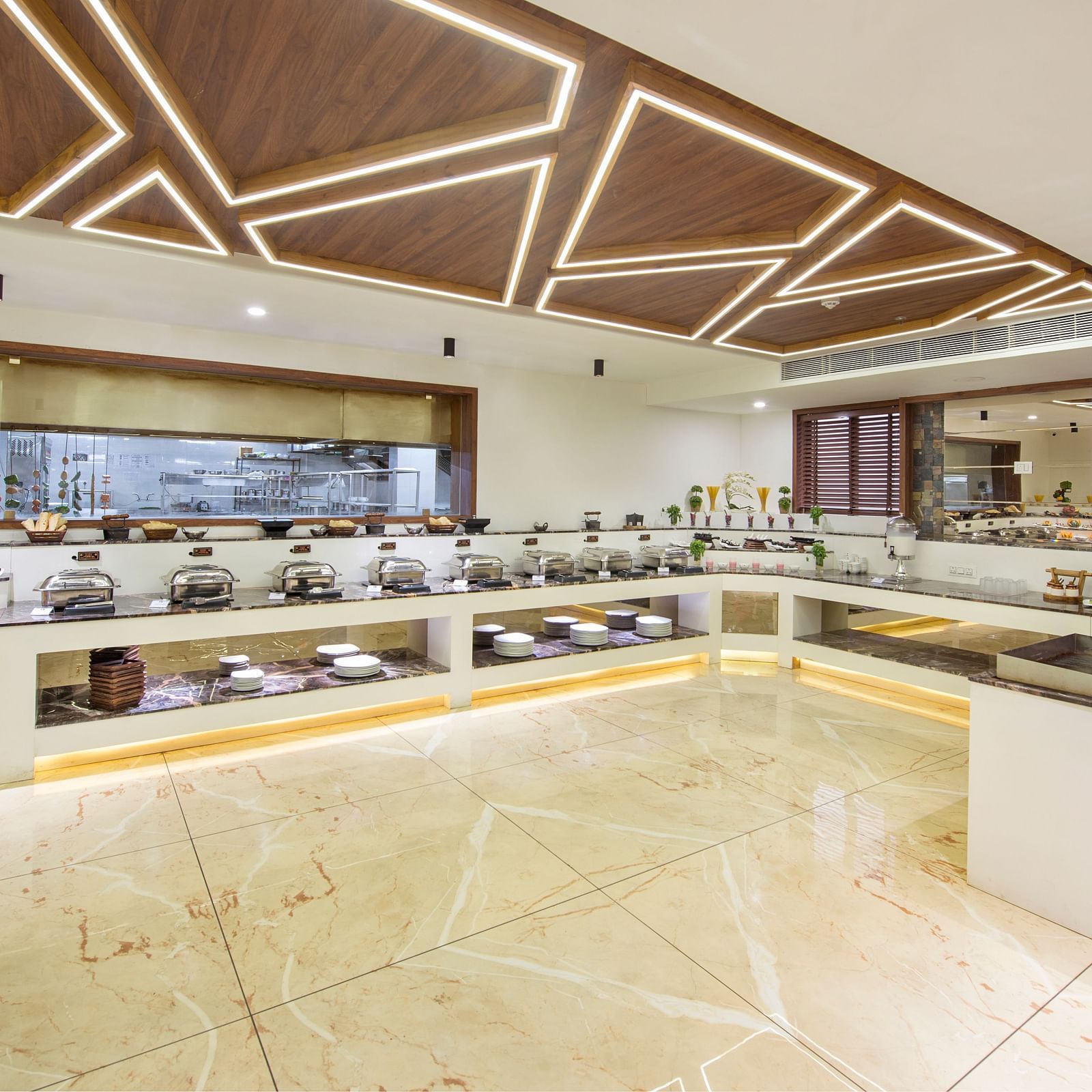 Modern hotel buffet area with a geometric ceiling design and sleek lighting at Lords Eco Inn Morbi.