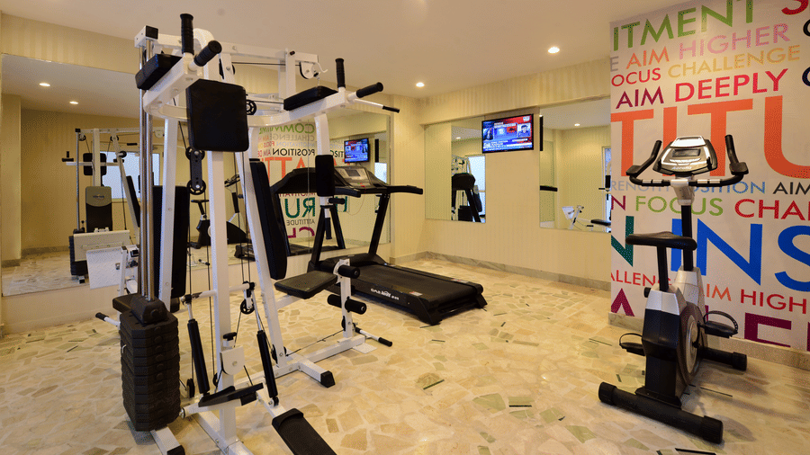 A gym with equipment, marble flooring and motivational quotes on the wall