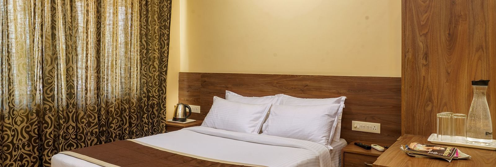 A warm and inviting hotel room with a king size bed, plush pillows, and a side table with a fruit bowl.