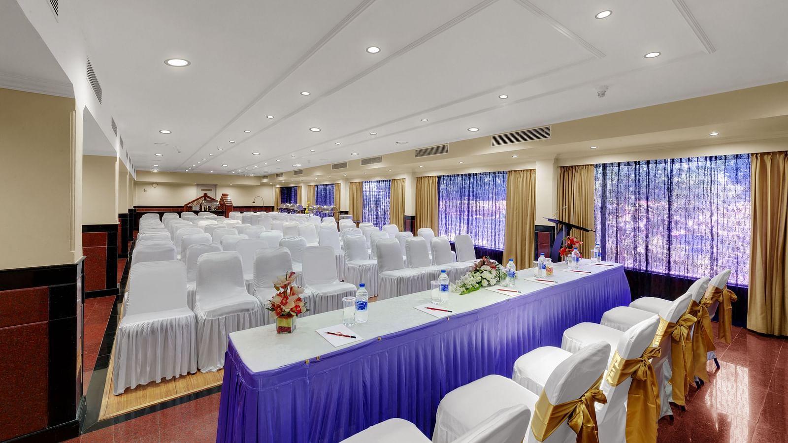 A top side angle shot of banquet hall with table and chairs at SRM Hotel Maram Malai Nagar, Chennai
