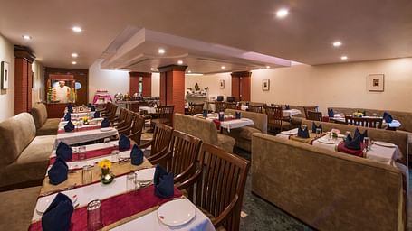 A warmly lit restaurant featuring multiple dining tables at Lords Inn Vadodara 