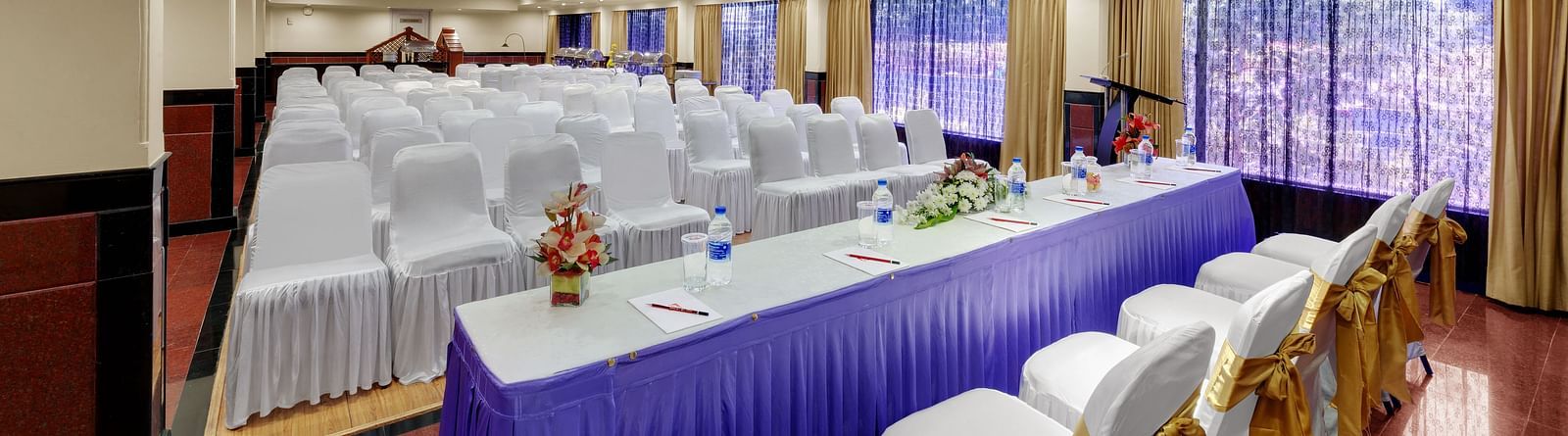 A top side angle shot of banquet hall with table and chairs at SRM Hotel Maram Malai Nagar, Chennai