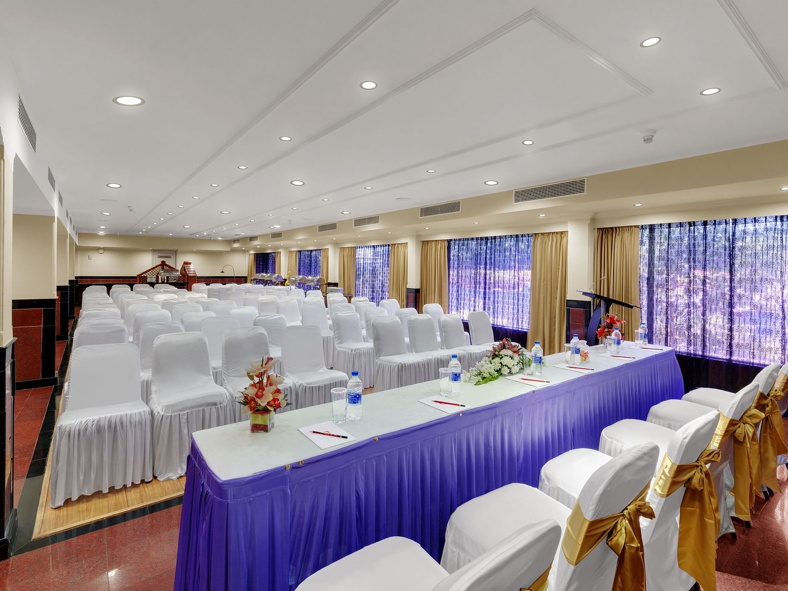 A top side angle shot of banquet hall with table and chairs at SRM Hotel Maram Malai Nagar, Chennai