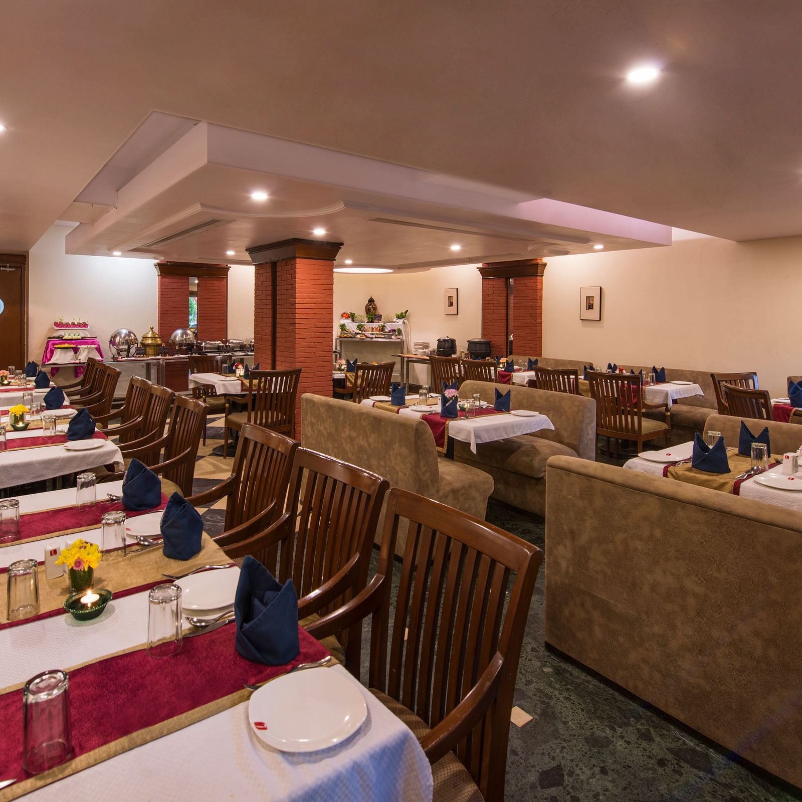 A warmly lit restaurant featuring multiple dining tables at Lords Inn Vadodara 
