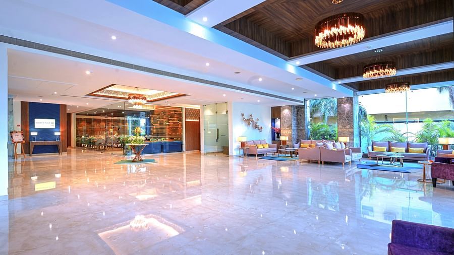 A vast hotel lobby with tiled floors, plush couches, and chandeliers hanging from the ceiling - Golden Tulip, Agra
