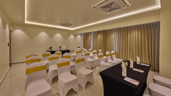 A beautifully lit banquet hall with chairs draped in white cloth positioned in front of a table