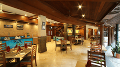 The interior of a Courtyard at Uday Samudra Leisure Beach Hotel showcasing wooden beams, tiled floors, and set tables ready for diners