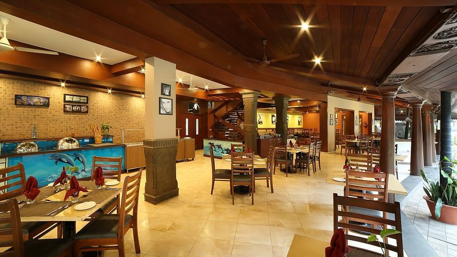 The interior of a Courtyard at Uday Samudra Leisure Beach Hotel showcasing wooden beams, tiled floors, and set tables ready for diners