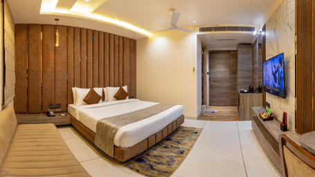 A room at Lords Inn Sangam, Bhopal with a neatly made bed, wooden paneled headboard, wall-mounted TV, and warm ceiling lighting.
