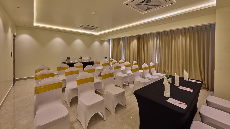 A beautifully lit banquet hall with chairs draped in white cloth positioned in front of a table