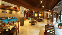 The interior of a Courtyard at Uday Samudra Leisure Beach Hotel showcasing wooden beams, tiled floors, and set tables ready for diners