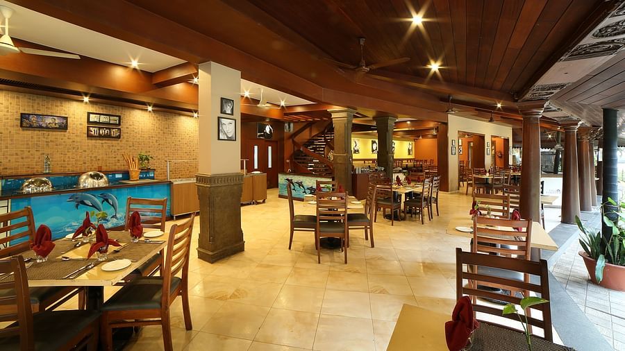 The interior of a Courtyard at Uday Samudra Leisure Beach Hotel showcasing wooden beams, tiled floors, and set tables ready for diners