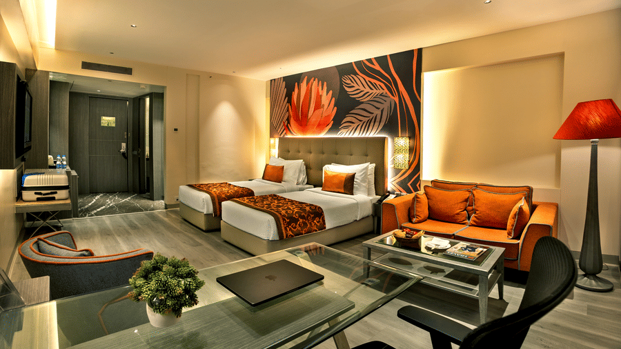 Executive Room at The Sonnet, Kolkata featuring twin beds, bedside tables, lounge seating and a television.