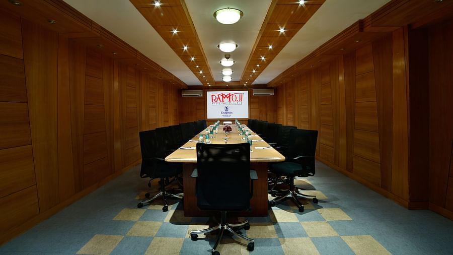 A modern boardroom with a long table, black chairs, and a projector screen at the end. - Tara, Comfort Hotel in Hyderabad - Ramoji Film City.
