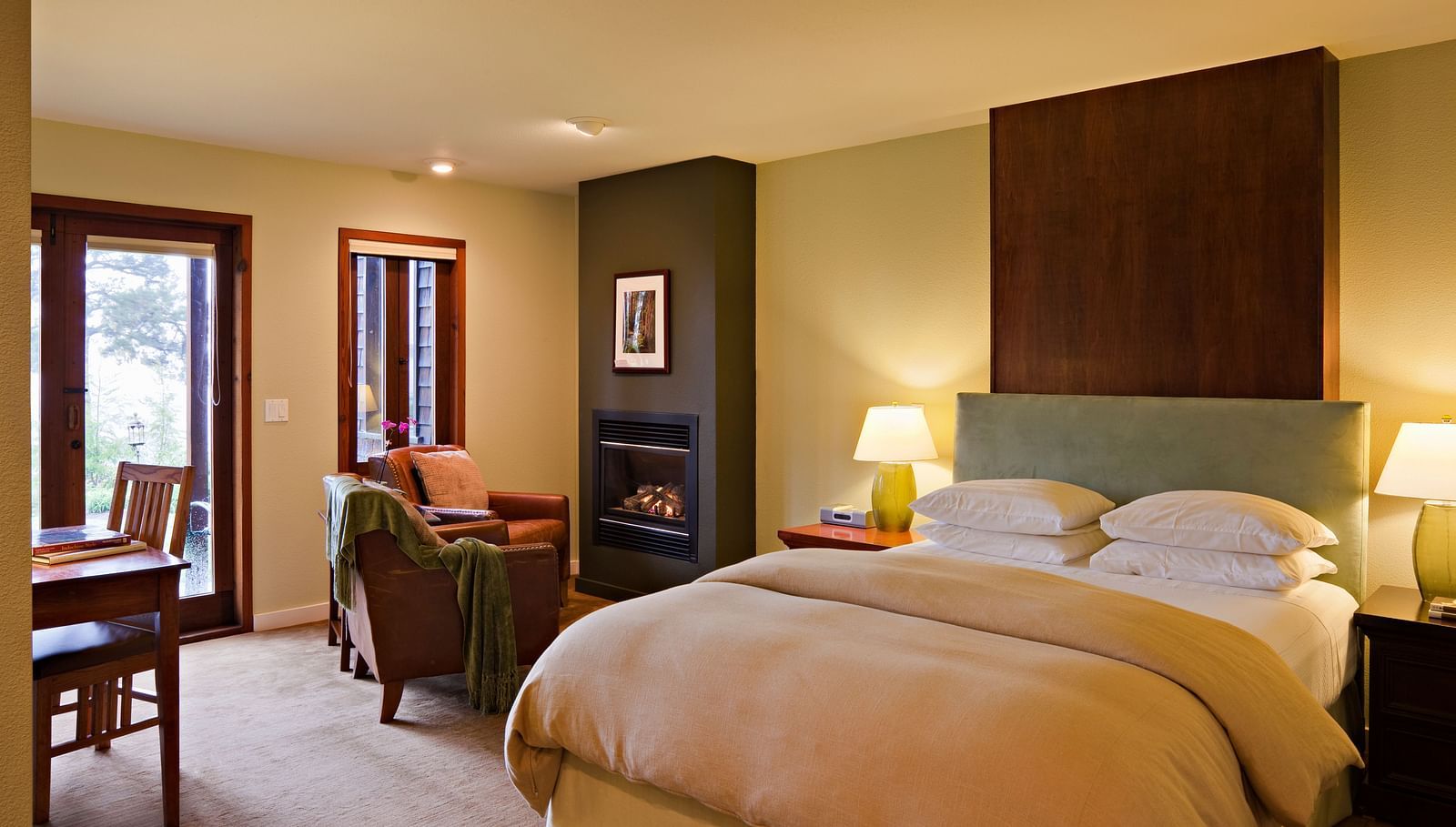 A hotel room with a double bed, cozy furniture and night lamps filling the room in warm lighting - Brewery Gulch Inn & Spa