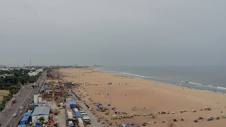 An overview of Marina Beach in Chennai with people, shops, road and vehicles in view.