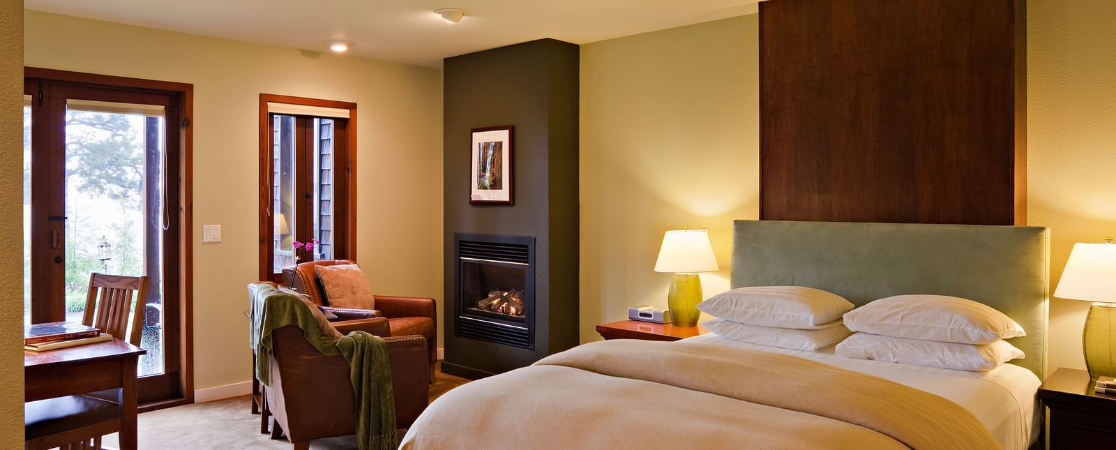 A hotel room with a double bed, cozy furniture and night lamps filling the room in warm lighting - Brewery Gulch Inn & Spa