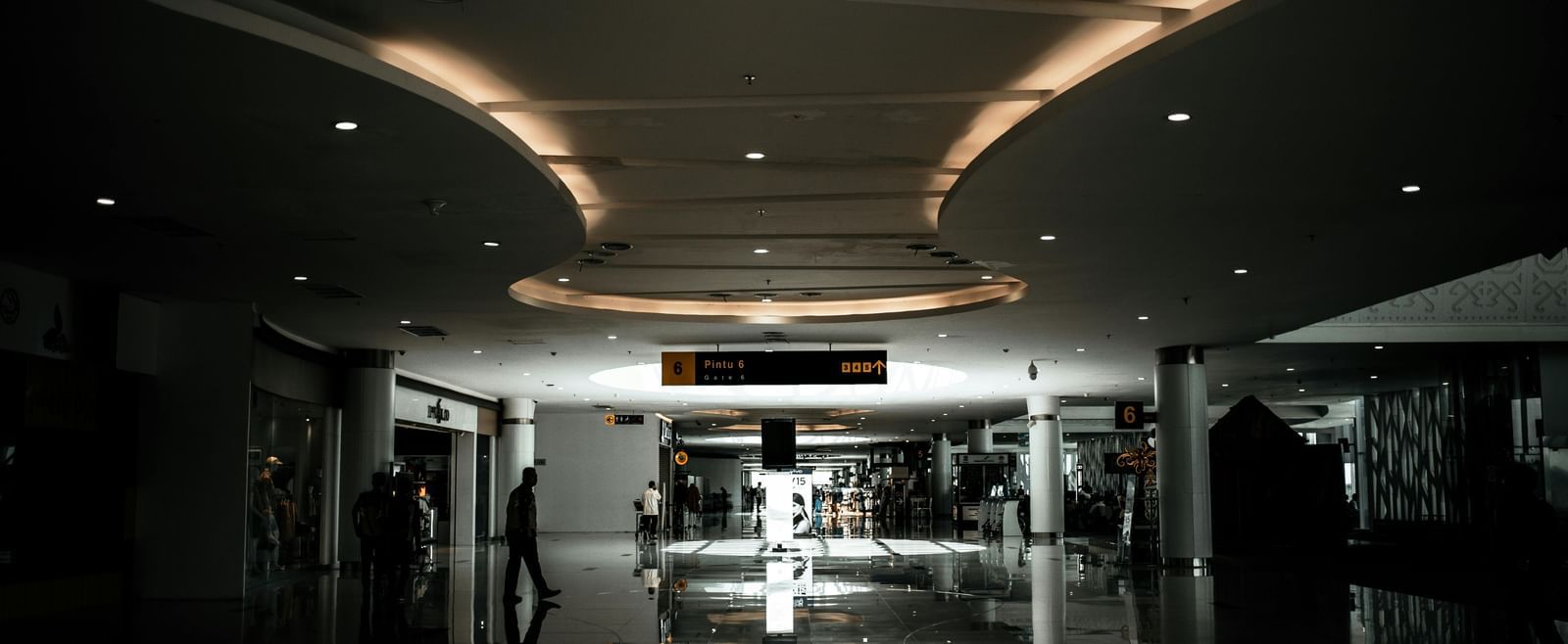 A dimly lit, wide hallway inside a building with a curved ceiling and a bright light source at the far end.