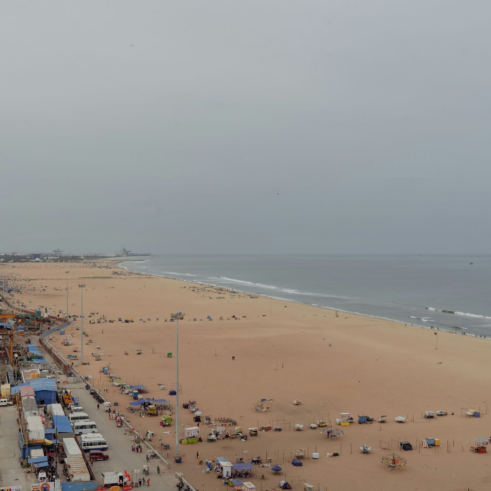 An aerial view of Marina Beach in Chennai with waves, beach, cars, roads all in view.