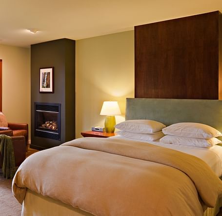 A hotel room with a double bed, cozy furniture and night lamps filling the room in warm lighting - Brewery Gulch Inn & Spa