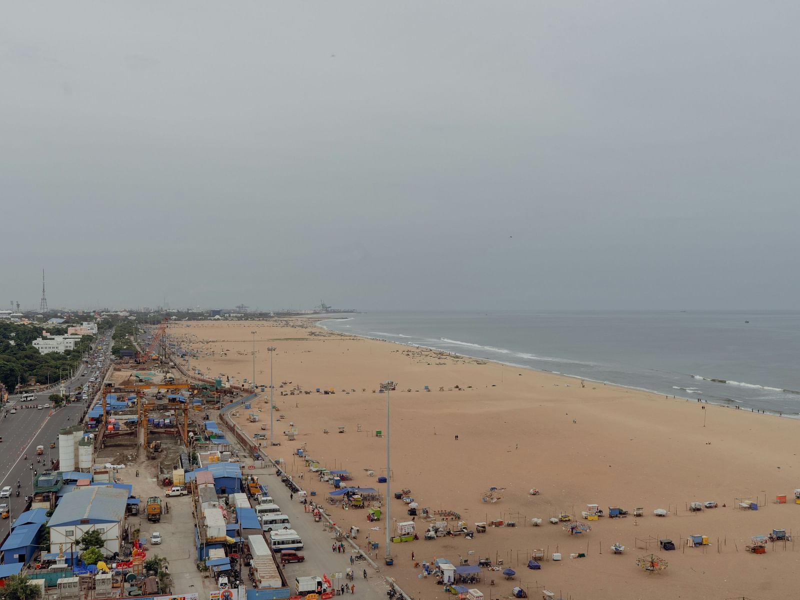 An aerial view of Marina Beach in Chennai with waves, beach, cars, roads all in view.
