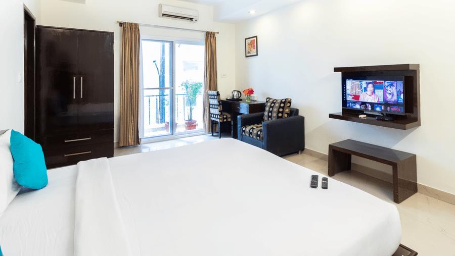 Cosy guest room with flat screen TV and wardrobe at Sanctum Suites Domlur Bangalore