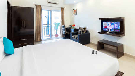 Cosy guest room with flat screen TV and wardrobe at Sanctum Suites Domlur Bangalore
