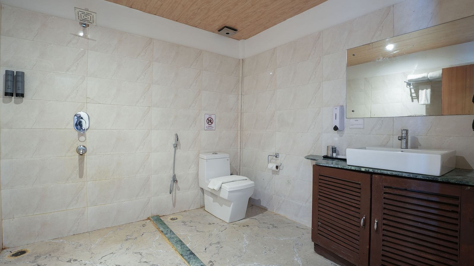 The spacious bathroom of the Premium room with balcony features a large washbasin with a mirror, and wooden storage space underneath at Summit Green Lake Tea Resort & Spa, Kaziranga