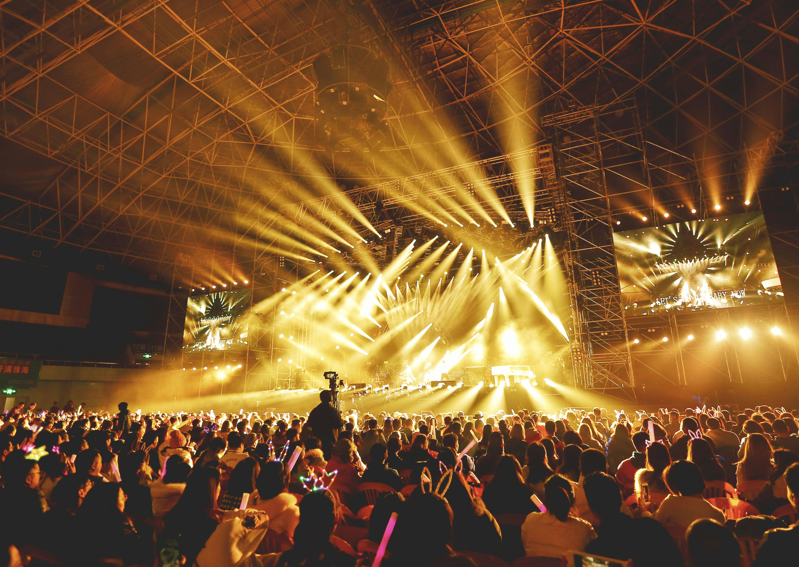 A concert audience under yellow stage lights during a live show