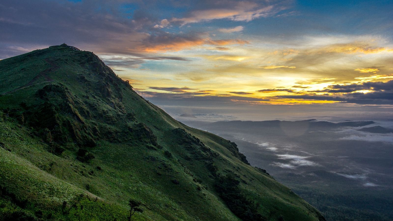 An overview of the green mountain in the western ghats with the sun setting in the background.