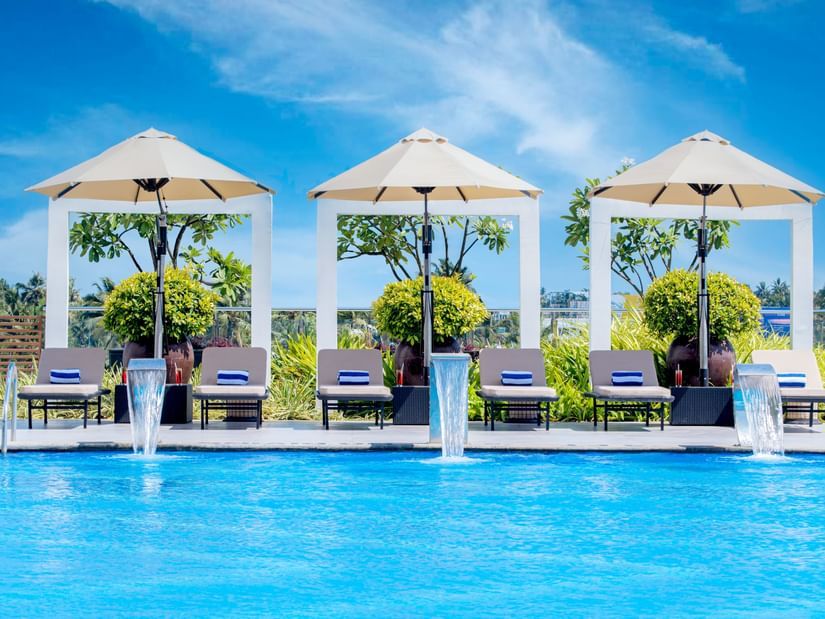 O By Tamara, Trivandrum - sunbeds under umbrellas beside the turquoise swimming pool in Trivandrum