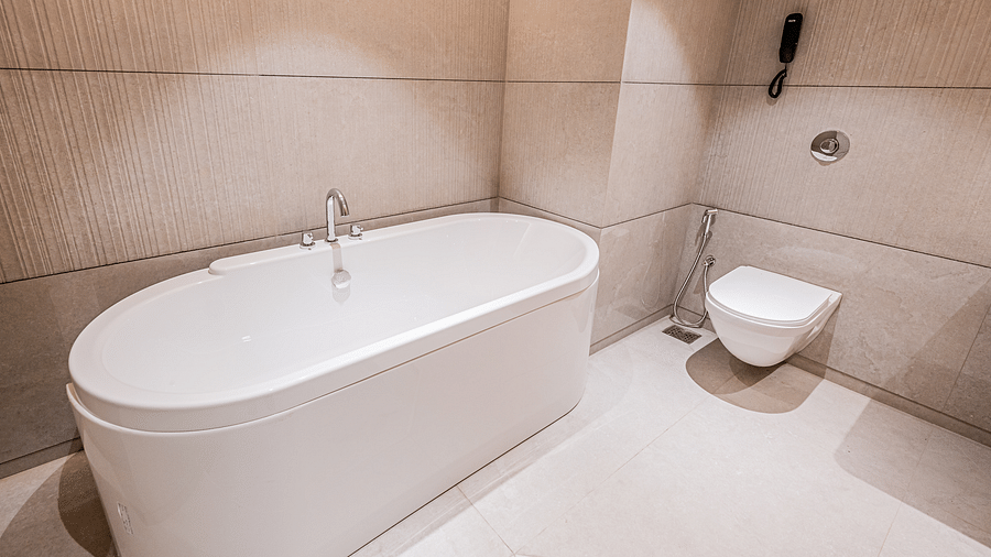 A spacious washroom at Indie Stays Mumbai International Airport features a bathtub on one side and a western toilet on the other.
