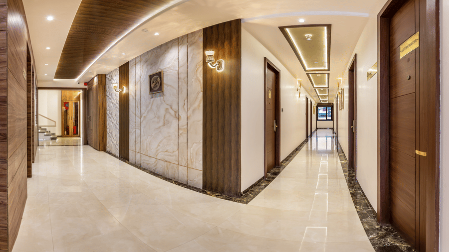 Elegant hotel corridor at Lords Inn Sangam, Bhopal with marble flooring, arched ceiling design, warm lighting, and wooden guest room doors.
