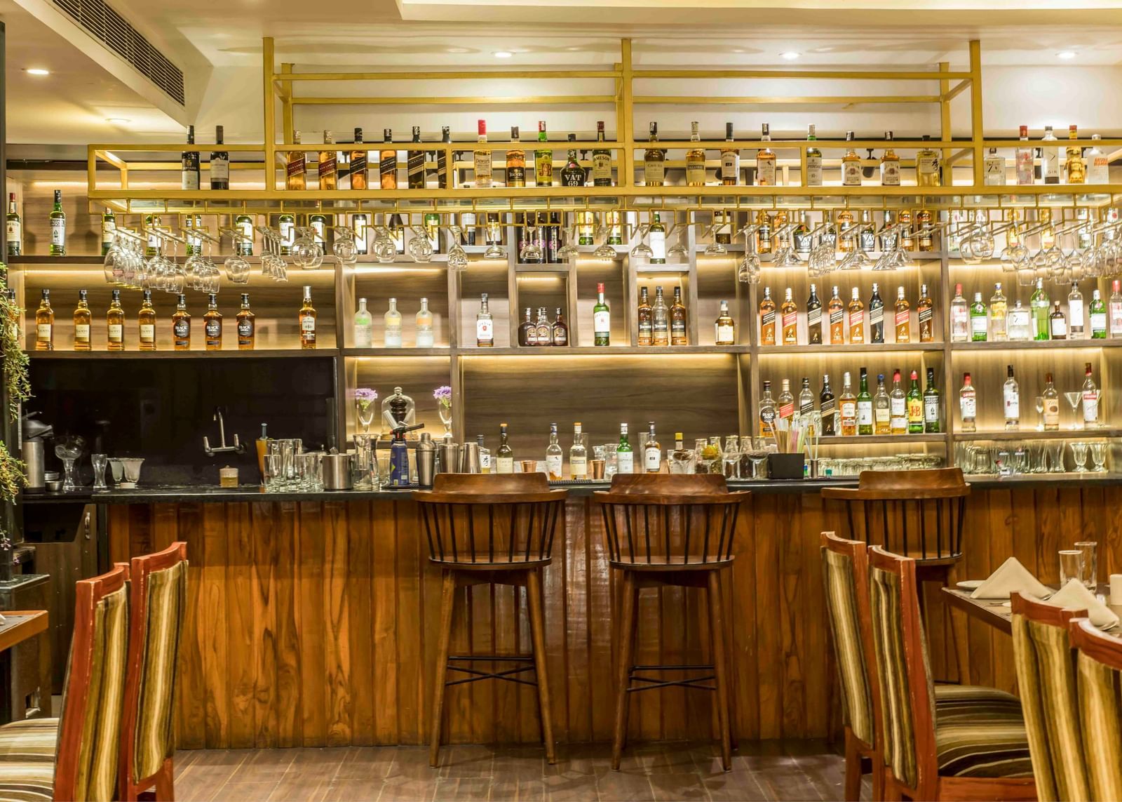 Well-lit hotel bar with a wide selection of bottles and several bar stools | The Citi Residenci Hotel Durgapur