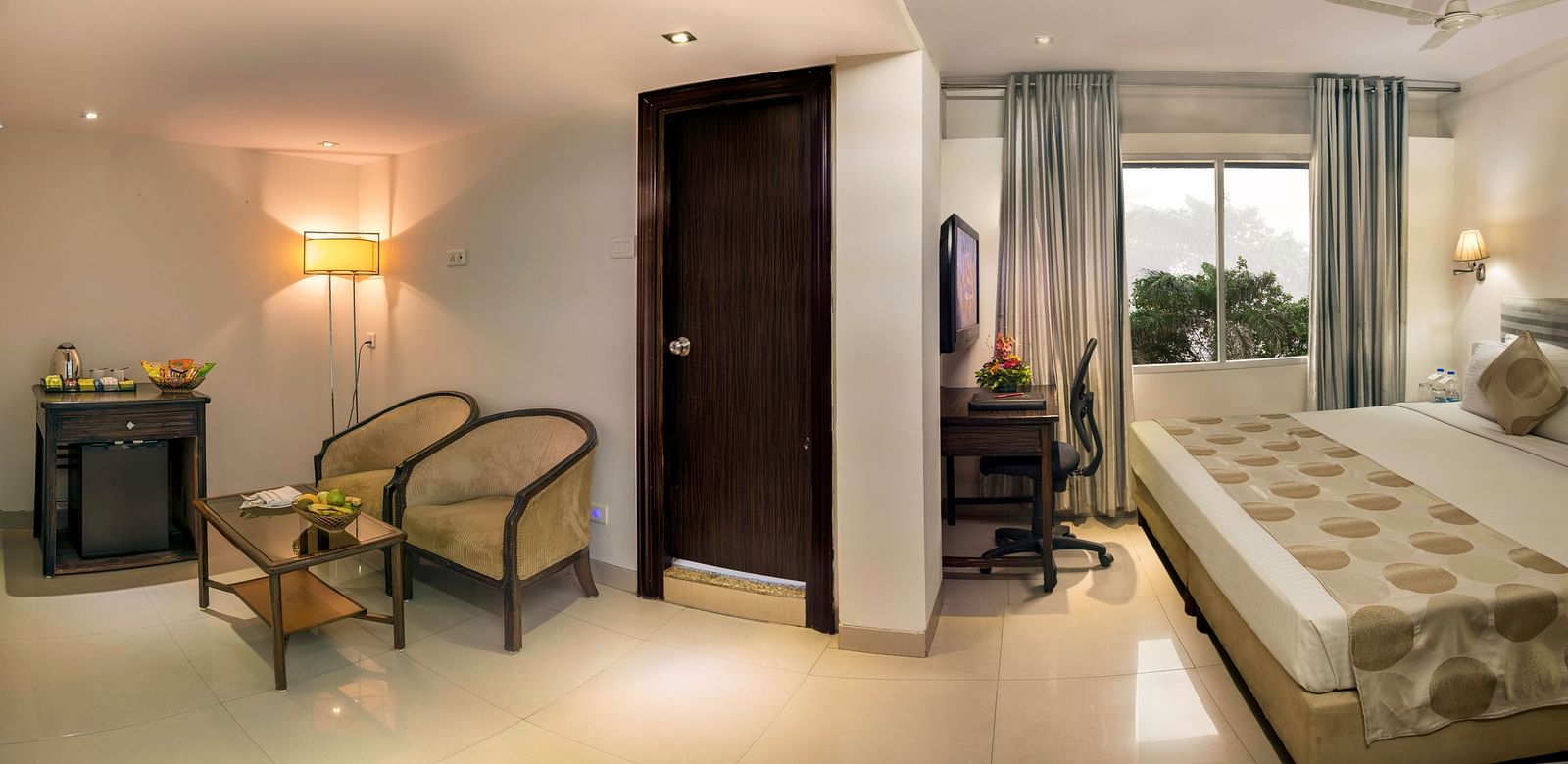 A hotel room with twin beds, armchairs, a desk, and soft lighting - Lords Eco Inn Dahej