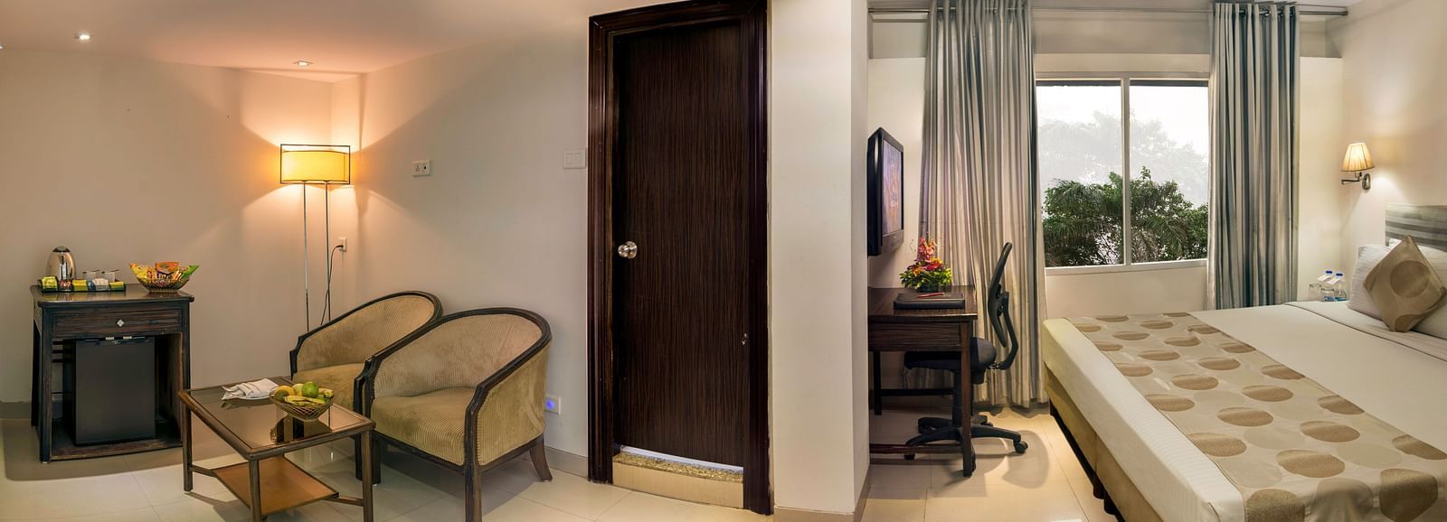 An elegant executive room with twin beds, armchairs, a desk, and a separate living space with pendant lights at Lords Eco Inn Dahej.