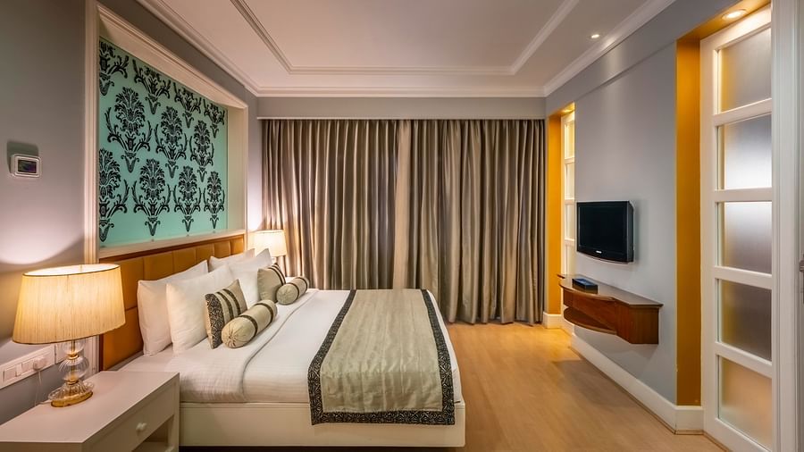 side view of the bed in the Junior Suite with curtains in the backdrop at Kenilworth Hotel, Kolkata