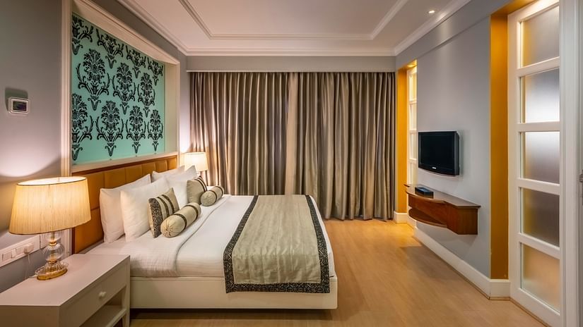 side view of the bed in the Junior Suite with curtains in the backdrop at Kenilworth Hotel, Kolkata
