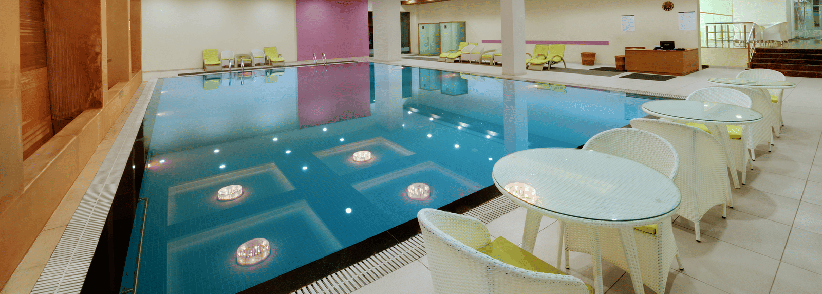 Indoor swimming pool with lounge chairs at Narayani Heights Hotel & Resorts, Ahmedabad.