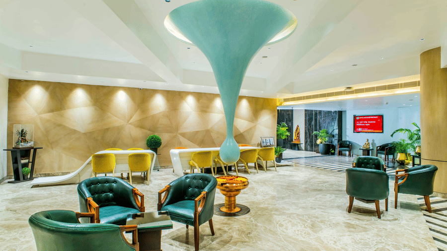 The hotel lobby of The Citi Residenci Hotel, City Centre Durgapur, with a large teardrop-shaped ceiling sculpture, stylish armchairs, and reception seating areas.