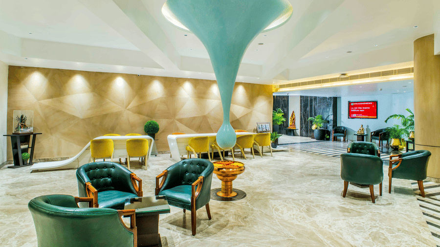 The hotel lobby of The Citi Residenci Hotel, City Centre Durgapur, with a large teardrop-shaped ceiling sculpture, stylish armchairs, and reception seating areas.