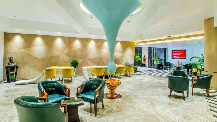 Stylish hotel lobby with teal armchairs, unique light fixtures, and a spacious layout | The Citi Residenci Hotel Durgapur
