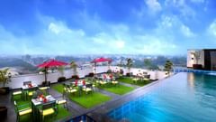An image of a rooftop swimming pool with a sky filled with dark clouds in the background - Golden Tulip, Agra