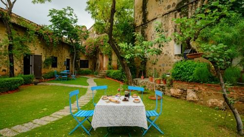 Hill Fort Kesroli 14th Century Alwar - image of a table with chairs on grass adjacent to a pathway