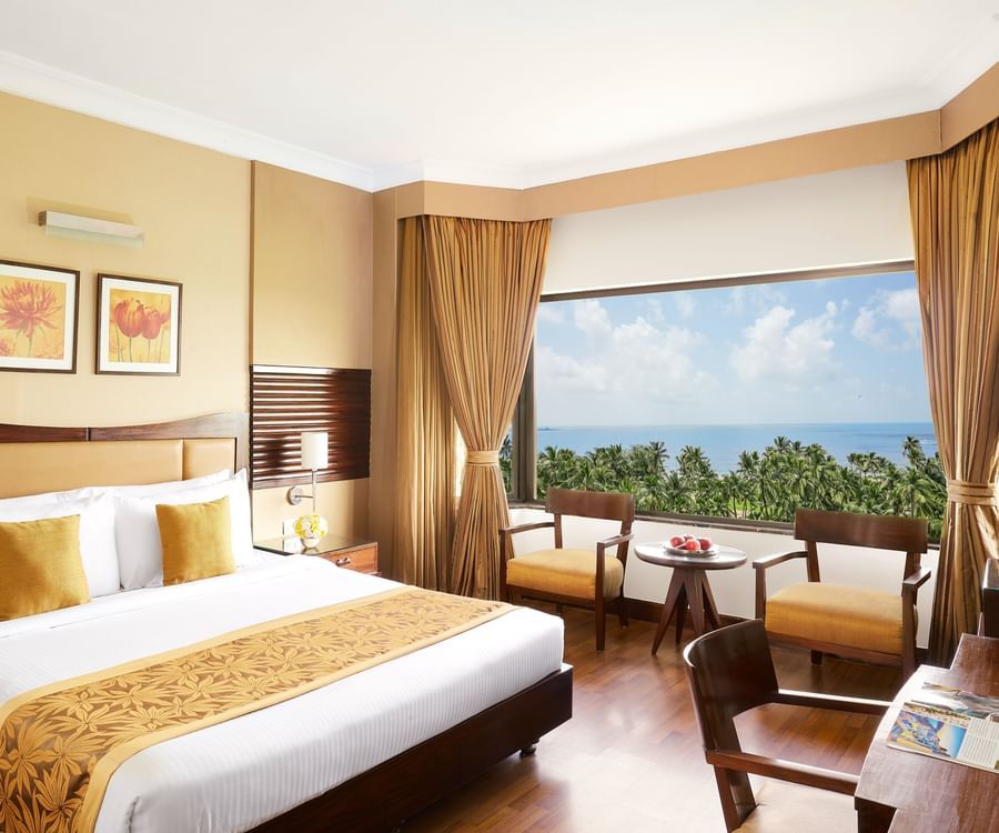 a double bed in a hotel room with a picturesque view from the floor to ceiling window at The Retreat Hotel and Convention Centre, for the perfect Weekend Staycation Near Mumbai