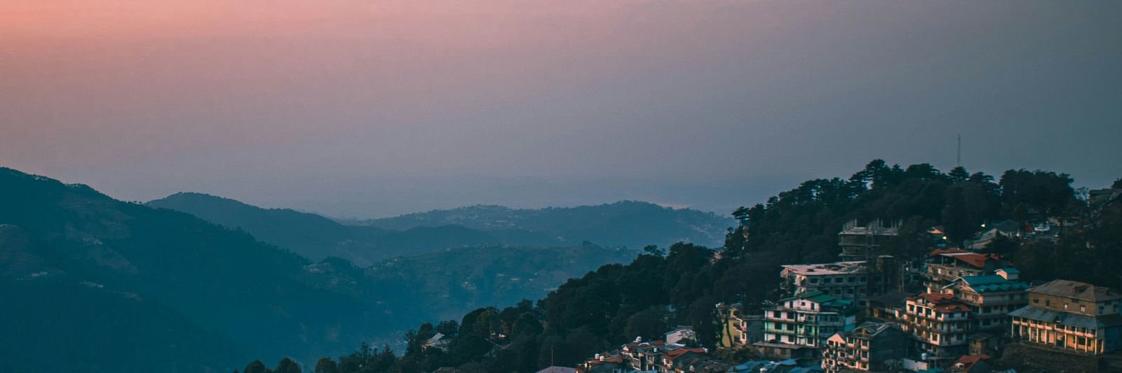 a hilly range on an evening with a beautiful sky with orange hues in the background in dalhousie