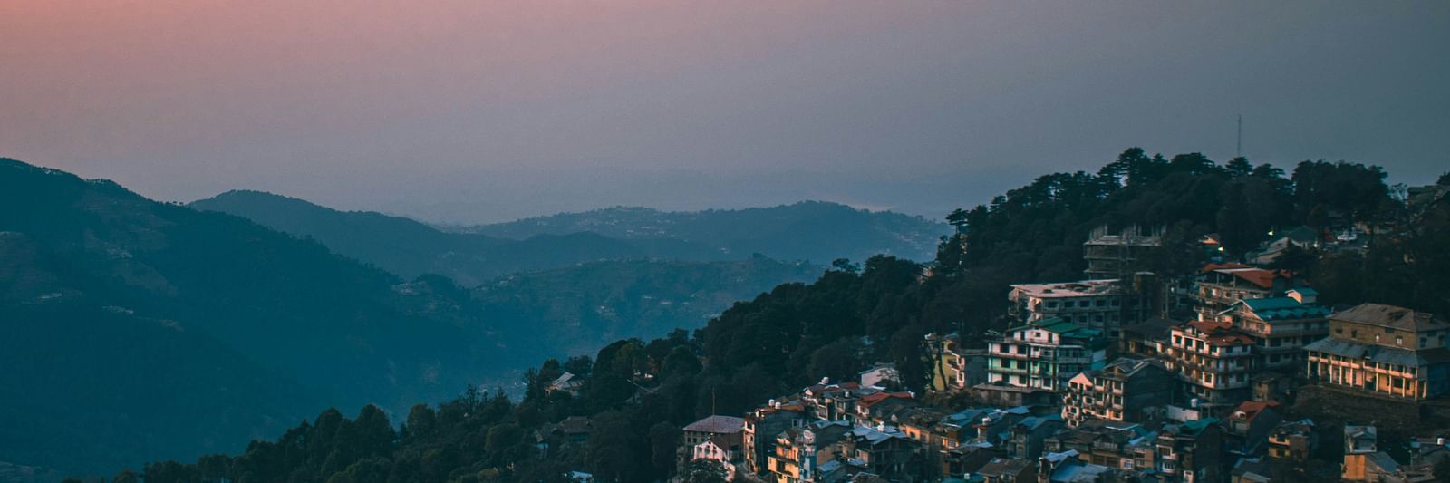 a hilly range on an evening with a beautiful sky with orange hues in the background in dalhousie