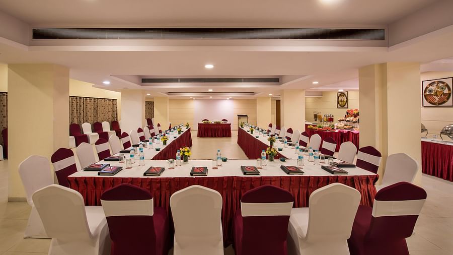 A brightly lit conference room is arranged with a long central table and numerous chairs set for a meeting - Lords Inn Vadodara